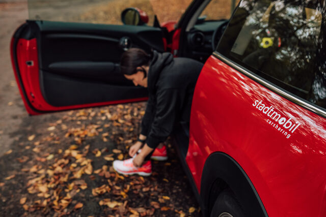 Frau bindet sich auf Fahrersitz eiens Autos Schuhe zu