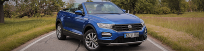 Blauer VW T-Roc steht auf der Straße, rechts und links daneben ein Feld